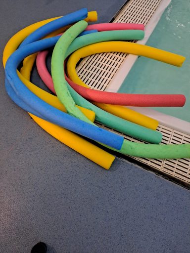 a pile of different coloured pool noodles